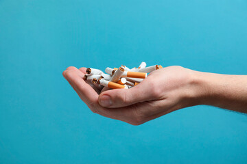 Stop smoking. Man holding broken cigarettes on light blue background, closeup