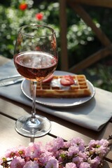 Delicious Belgian waffle with fresh strawberries and wine served on table in spring garden