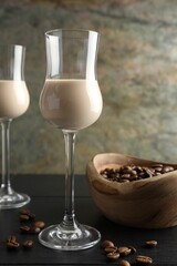 Coffee cream liqueur in glasses and beans on black wooden table