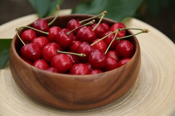 Tasty ripe red cherries in wooden bowl outdoors