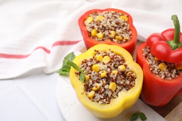 Quinoa stuffed bell peppers and basil on white table, closeup. Space for text