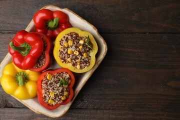 Quinoa stuffed bell peppers and basil in baking dish on wooden table, top view. Space for text