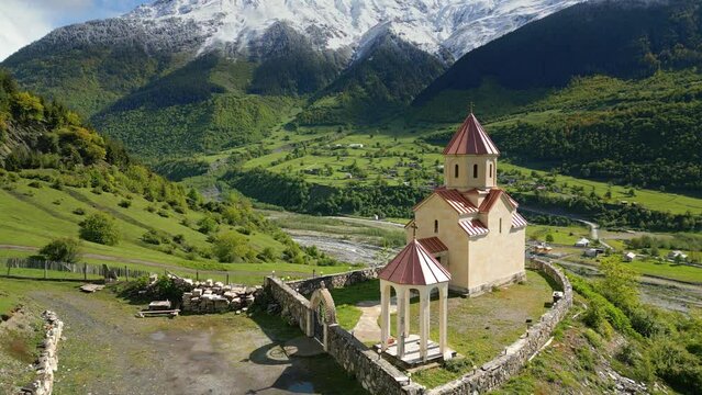 small church on alpine green meadow, backdrop snowy peak, , aerial view