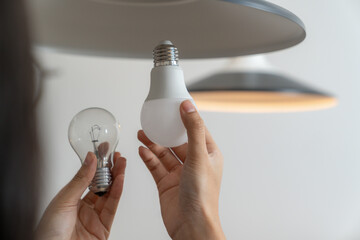 The young woman is changing light bulbs at home