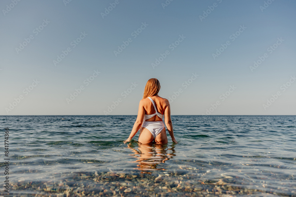 Canvas Prints a woman is standing in the ocean wearing a white bikini