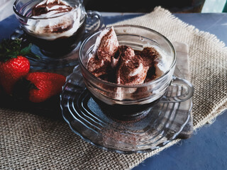 coffee with whipped cream and cocoa powder in glass cup and gray  background