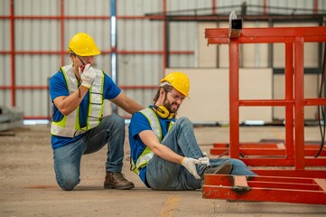 A worker is injured at a construction site and his coworker is calling for help.