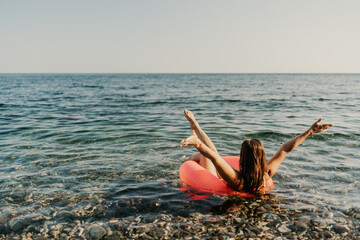 A woman is floating in a red inflatable tube in the ocean