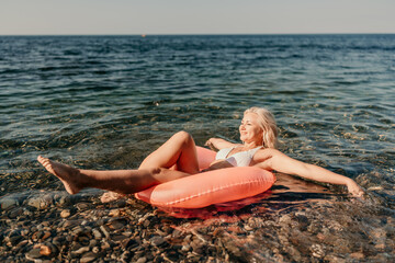 A woman is floating on a red inflatable raft in the ocean