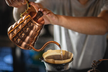 drip coffee, Barista making drip coffee by pouring spills hot water on coffee ground with prepare filter from copper pot to glass transparent chrome drip maker on wooden table in cafe shop