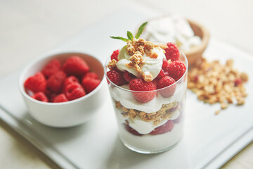Breakfast, food and yogurt with fruit in glass for healthy diet, nutrition and cereal in morning. Raspberry, vitamin and dairy in clear container with protein for weight loss, vegan meal and snack