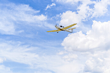 Single engine ultralight plane flying in the blue sky with white clouds