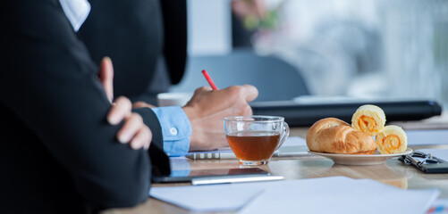 A business meeting with a cup of tea and croissants on the table.