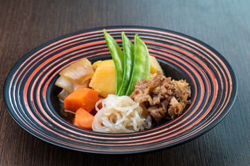 A bowl of Japanese beef stew with potatoes, carrots, and onions.