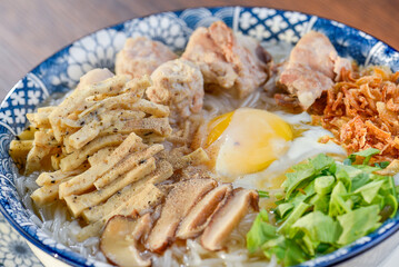 A bowl of Vietnamese chicken noodle soup with sliced chicken, meatballs, and a soft-boiled egg.