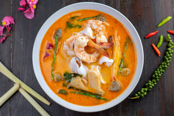 A bowl of Tom Yum soup with shrimp, squid, and mushrooms.
