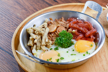 A photo of a plate of food that has three eggs, sausage, and other breakfast food items.