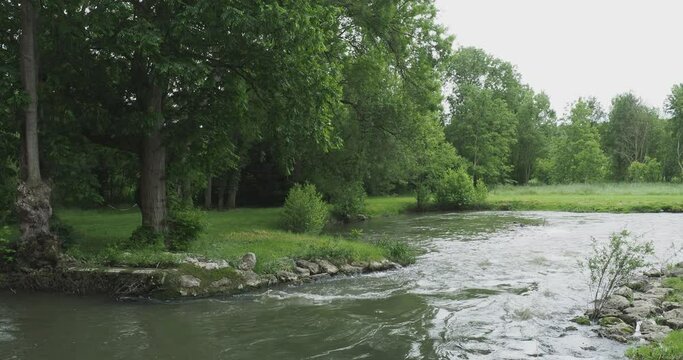 Paysage bucolique de Touraine. Un bras sinueux de l'Indre au d&eacute;bit rapide traversant une clairi&egrave;re bord&eacute;e d'arbres le long de prairies verdoyantes
