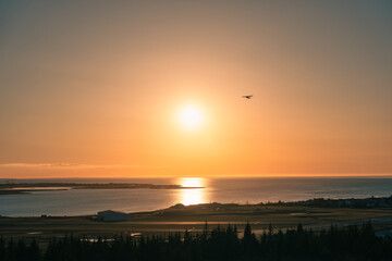 Propeller plane flying with colorful sundown on coastline