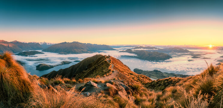Sunrise shining over summit of Roys Peak and foggy mountain over Lake Wanaka in autumn at New Zealand