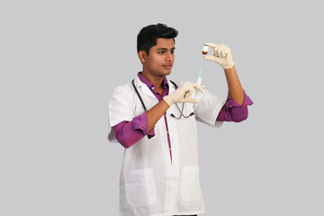 oung Indian male doctor with stethoscope on his neck in medical gloves fills the syringe with...