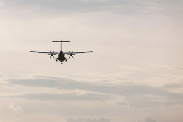Airplane flying over the beautiful blossom meadow at sunset. Travel, vacation, and freedom concepts.