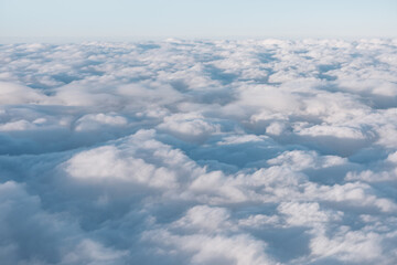 Aerial view of fluffy white clouds from an airplane window. Sky view while flying in a plane