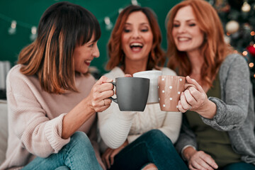 Coffee, friends and women on couch for Christmas celebration and toast together for vacation in...