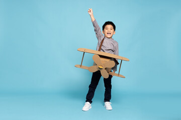 Asian little boy aviator playing and raise hand with cardboard airplane isolated on blue sky...