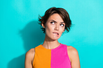Photo of uncertain unsure woman wear pink orange top biting lip looking empty space isolated teal...