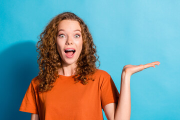 Photo portrait of happy red hair girl demonstrate her handmade surprised holding arm product empty space isolated on blue color background