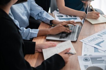 Multiracial analyst team use BI dashboard data to analyze financial report on meeting table. Group of diverse business people utilize data analysis by FIntech for success business marketing. Concord