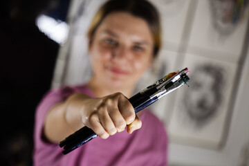 Artistic girl holding many dirty colorful used brushes.