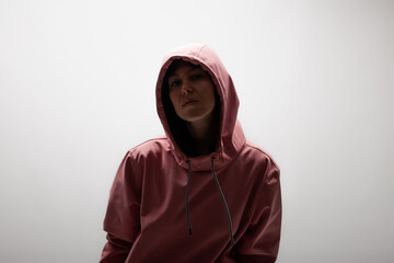 Serene young woman in a pink hoodie against a neutral background