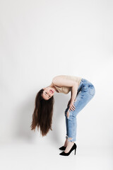 Young woman playfully bending forward in casual attire on white background