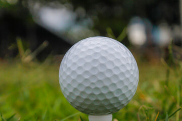 Golf ball set on tee with green bokeh background