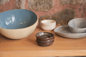 A charming arrangement of handmade ceramic dishware showcased elegantly on a wooden shelf