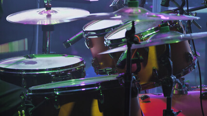 A professional drum kit captured from an angle showcasing three tom-toms with worn-out batter-heads...