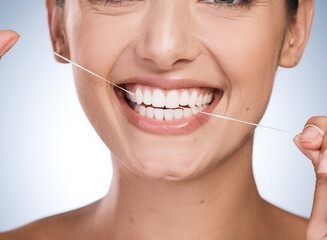 Woman, mouth and floss teeth in studio, orthodontics and cosmetics for smile on blue background. Female person, dental health and string for grooming, cleaning and self care or thread for plaque