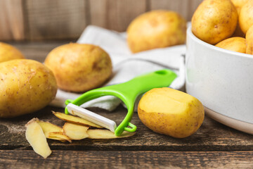 Young potatoes. Raw potatoes and knife on a wooden background.Peel potatoes.Harvesting collection. organic, freshly dug potatoes. Agricultural background. Vegan. Vegetables.Place for text.Copy space