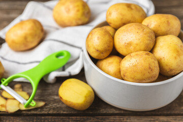 Young potatoes. Raw potatoes and knife on a wooden background.Peel potatoes.Harvesting collection. organic, freshly dug potatoes. Agricultural background. Vegan. Vegetables.Place for text.Copy space