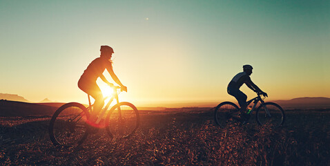 Sunset sky, silhouette and people on bicycle together with adventure, race and exercise in nature. Cycling, fitness and friends with mountain bike in evening for outdoor workout, trip and grass path