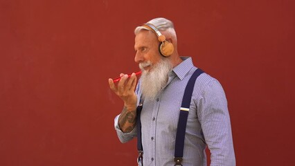 Senior hipster man using mobile phone for sending voice mail message - Joyful elderly person and technology concept 