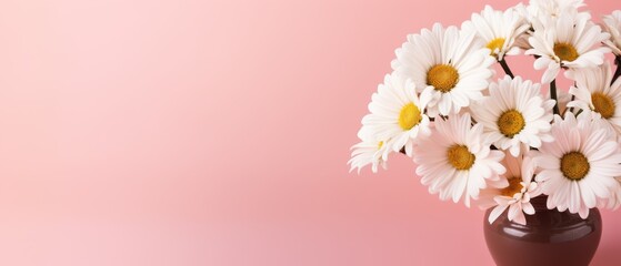 Obraz premium A bouquet of white daisies in a vase on a pink background. The flowers are arranged in a way that they are all facing the same direction, giving the impression of a unified and harmonious display