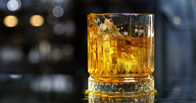 Super slow motion macro of transparent fresh cool ice bounced by bartender while preparing an old malt bourbon Whiskey cocktail at 1000 fps.