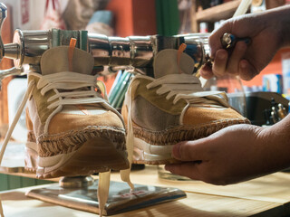 Shoemaker's hands placing shoes on lasts to take proper shape. Trades, business.