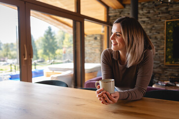 A moment of relaxation with coffee at home, a happy young woman takes a break from her duties and reflects