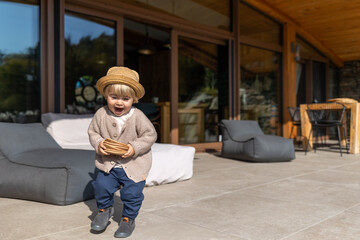 A child playing on the terrace in front of his house enjoys the garden on a sunny day