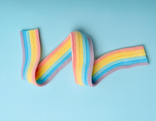 Creative healthy eating food concept photo of rainbow candy belt on blue background.