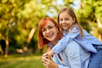 Portrait of two lovely ladies, mother and daughter spending time in the park, having fun.